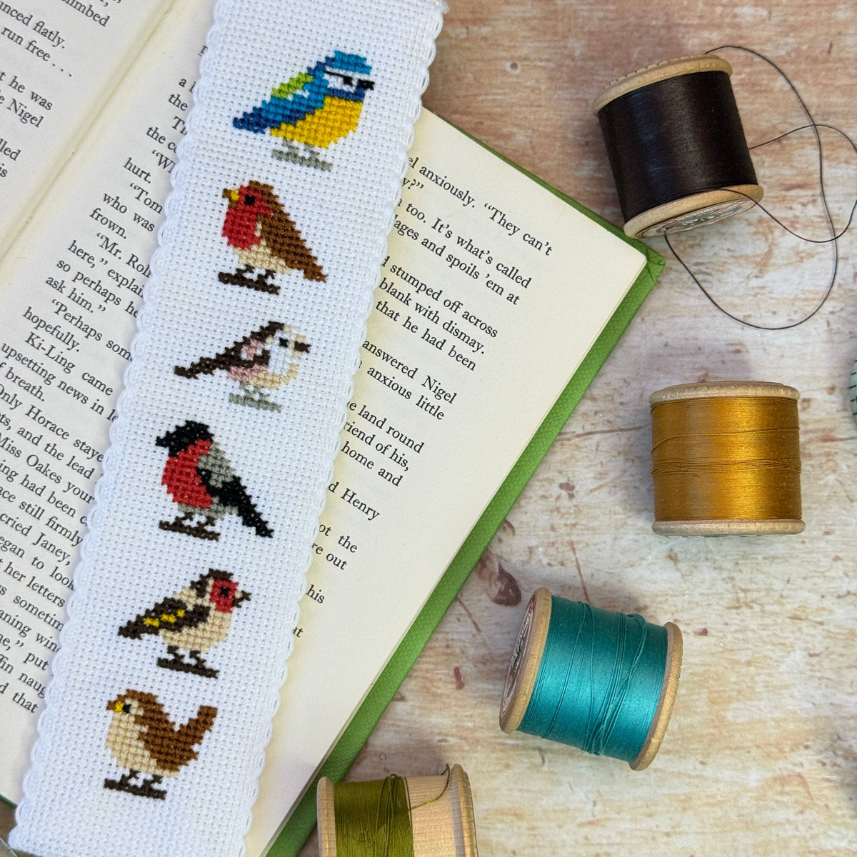 Garden Birds Cross Stitch Bookmark Kit finished embroidered bird bookmark marking the pages of an open book