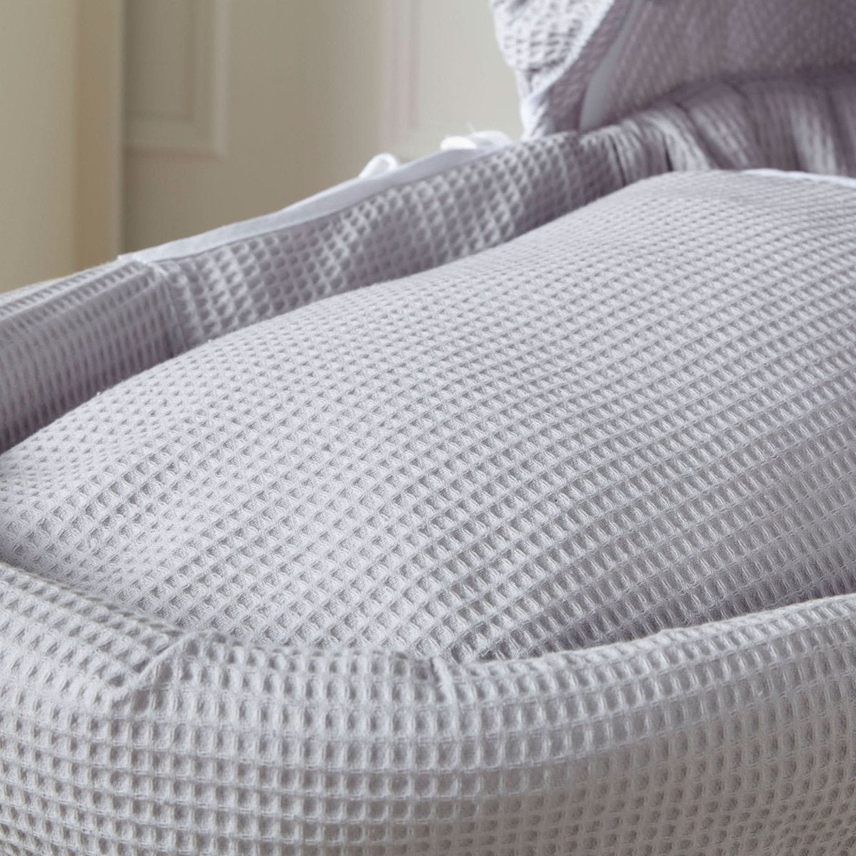 Grey Waffle White Wicker Baby Moses Basket close-up showing the soft textured grey waffle bedding