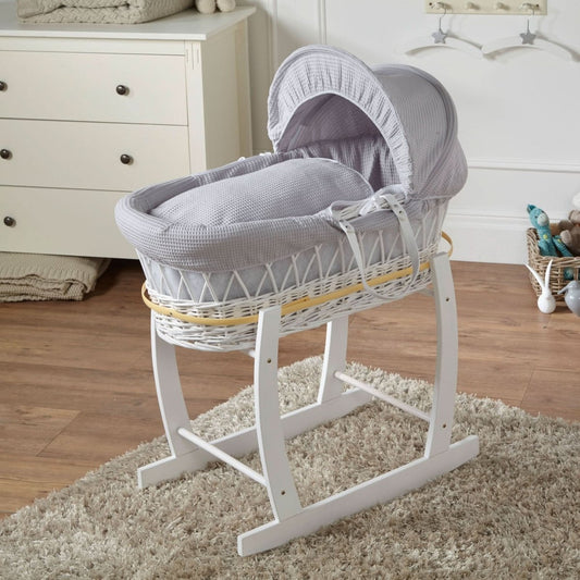 Grey Waffle White Wicker Baby Moses Basket with wooden stand and coordinating grey bedding in a neutral nursery setting