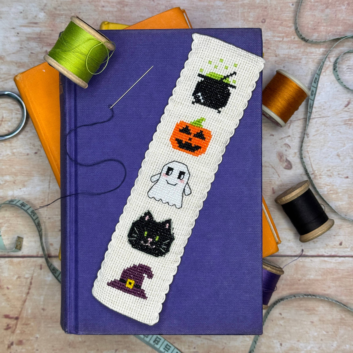 Hallowe'en Cross Stitch Bookmark Kit finished spooky bookmark styled on a purple book with colourful sewing threads