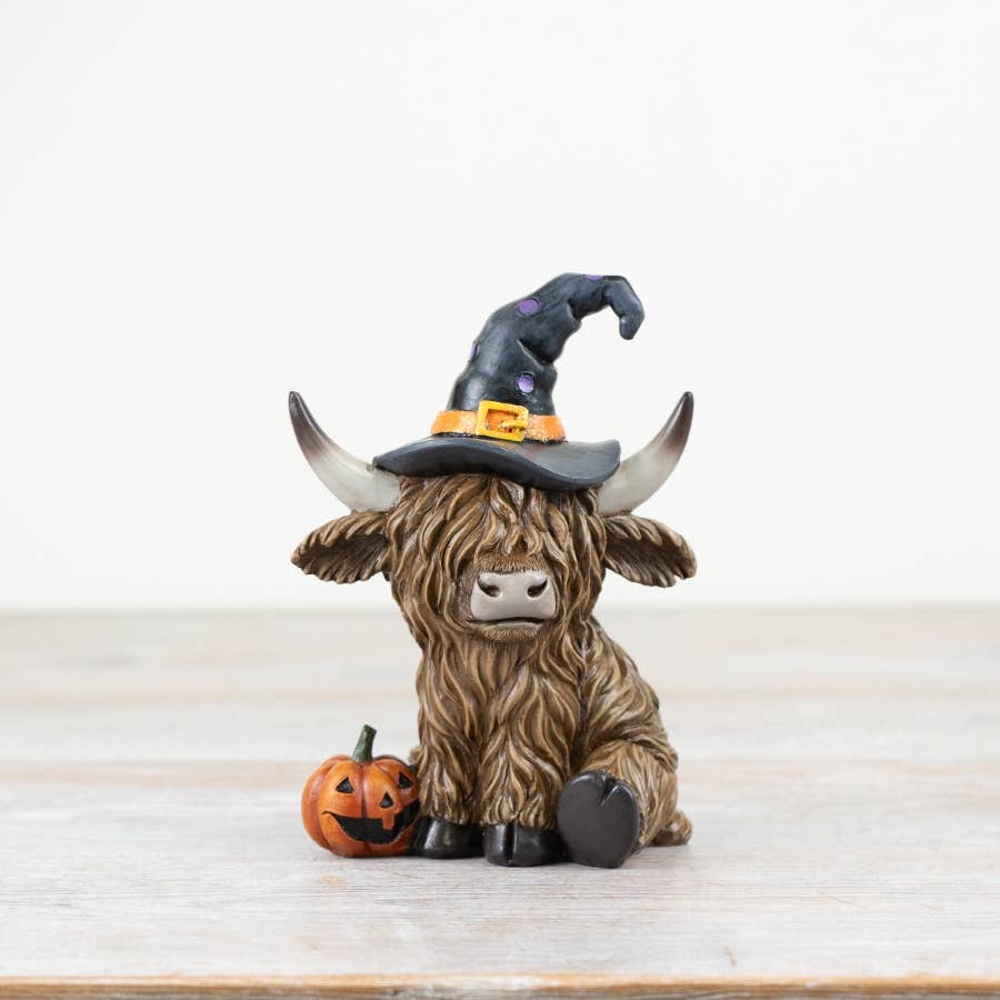 Halloween Highland Cow 13cm wearing a crooked black witch's hat and sitting beside an orange pumpkin