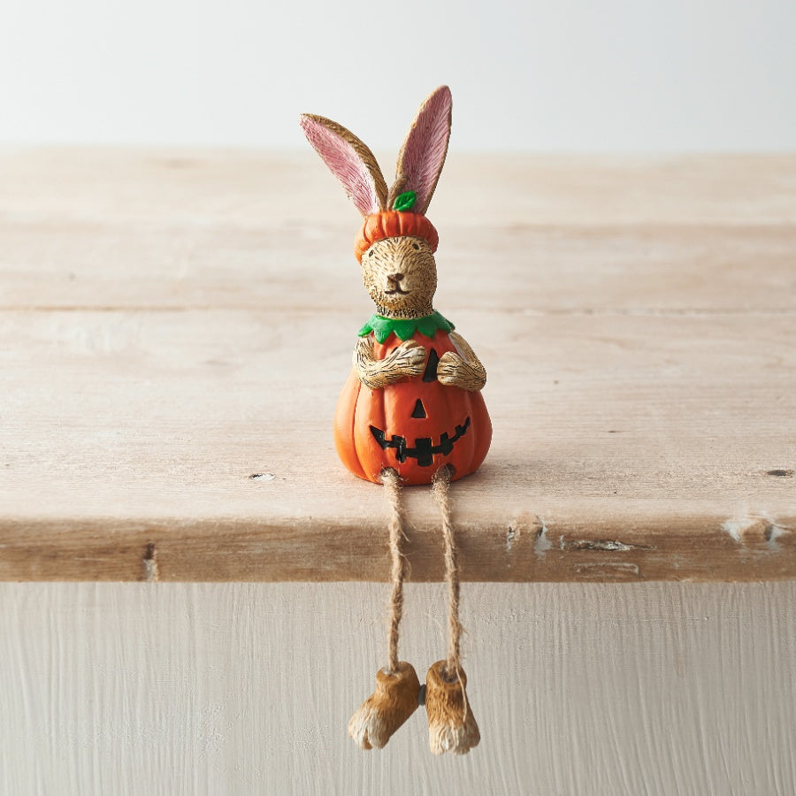 Jasper Rabbit Pumpkin Shelf Sitter in an orange jack-o'-lantern costume with dangling jute-string legs