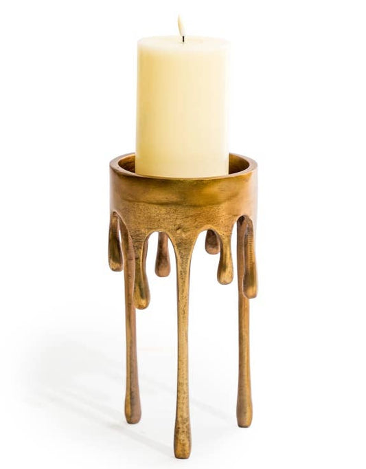 Large Gold Dali Drip Candle Holder with elongated molten-wax effect legs and cream pillar candle against a white background