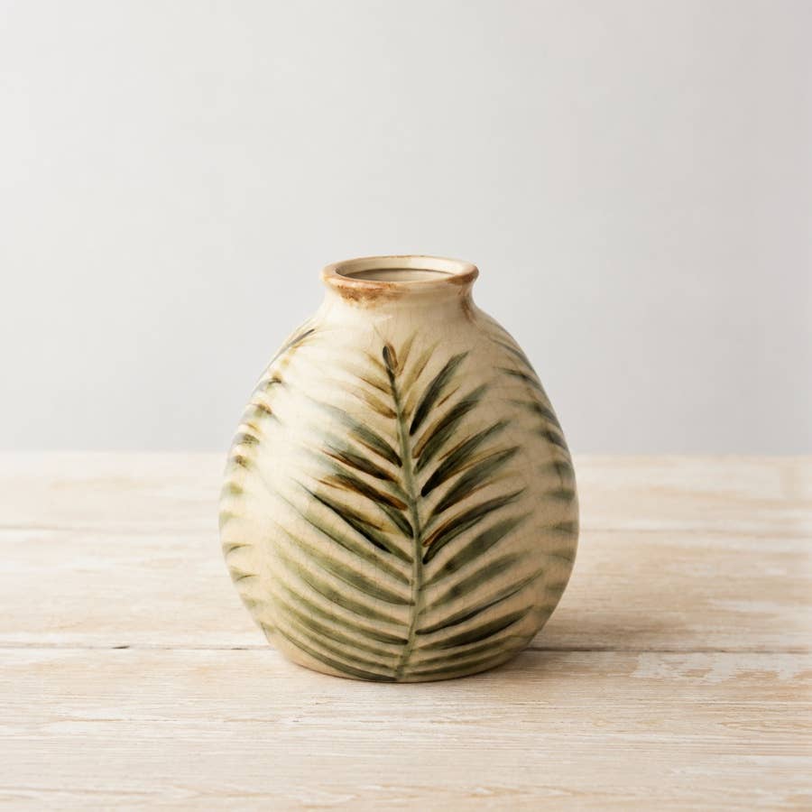 Letty Vase 18cm in glazed ceramic, featuring a rounded silhouette with raised palm-leaf detailing in soft green and cream tones, displayed on a wooden surface.