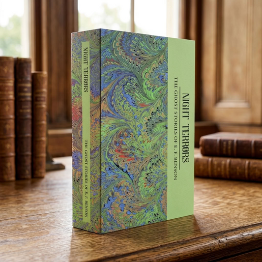 Night Terrors: The Ghost Stories of E. F. Benson paperback on an antique wooden desk in a traditional library