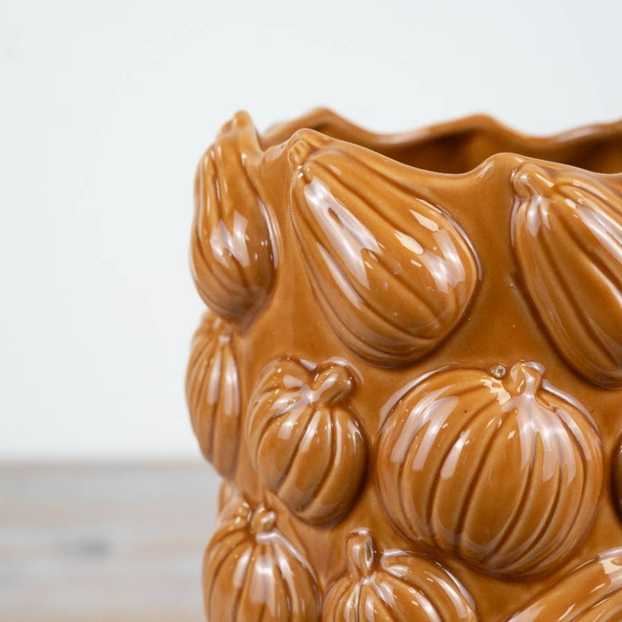 Close-up of textured pumpkin design on orange ceramic vase
