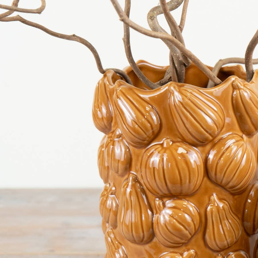 Close-up of textured pumpkin design on orange ceramic vase
