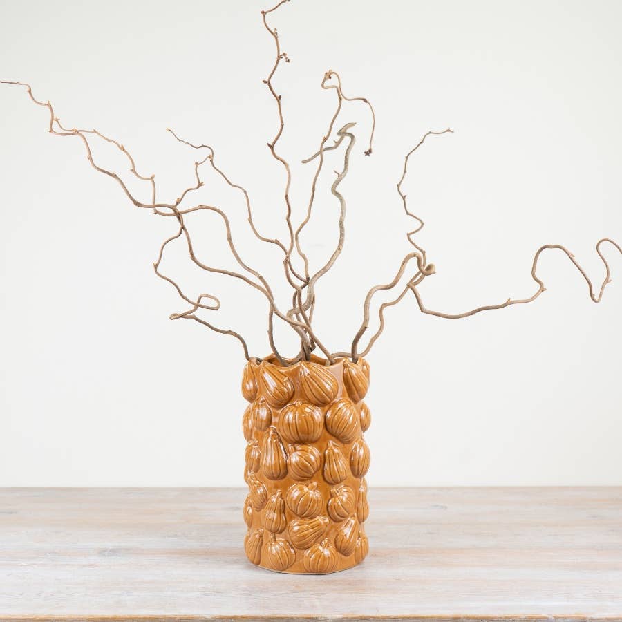 Tall orange pumpkin ceramic vase displayed with autumn branches
