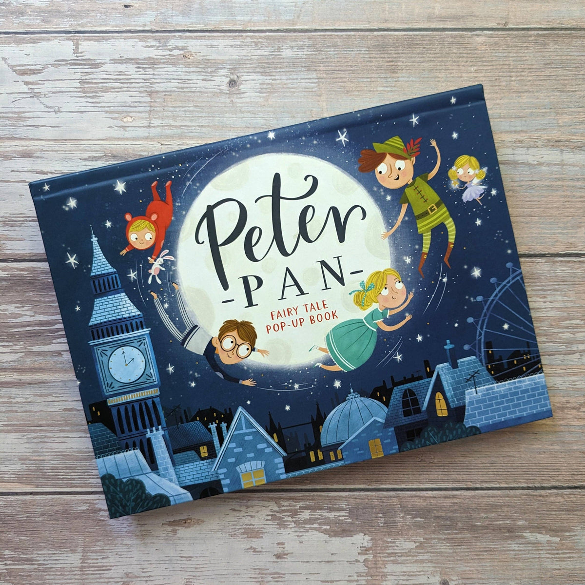Peter Pan children's pop-up book showing its illustrated front cover against rustic wooden boards