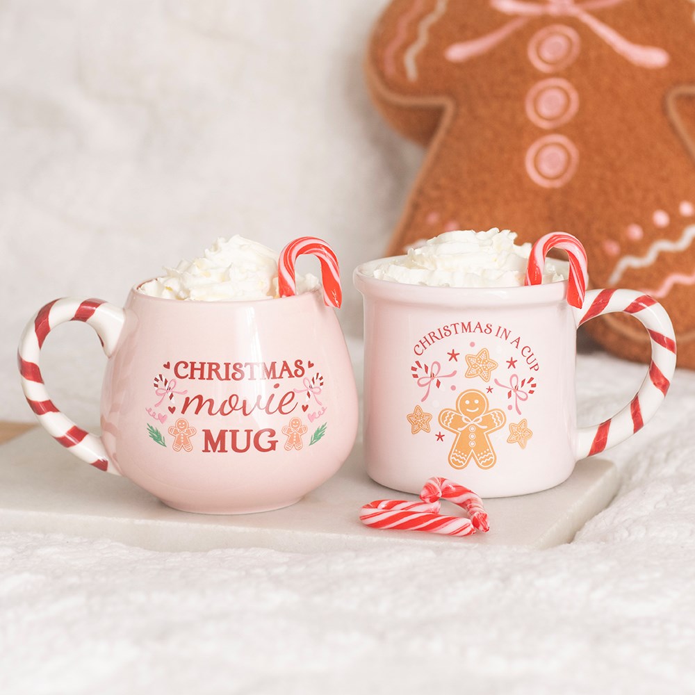 Pink Christmas Movie Mugs displayed with festive gingerbread decorations and candy canes