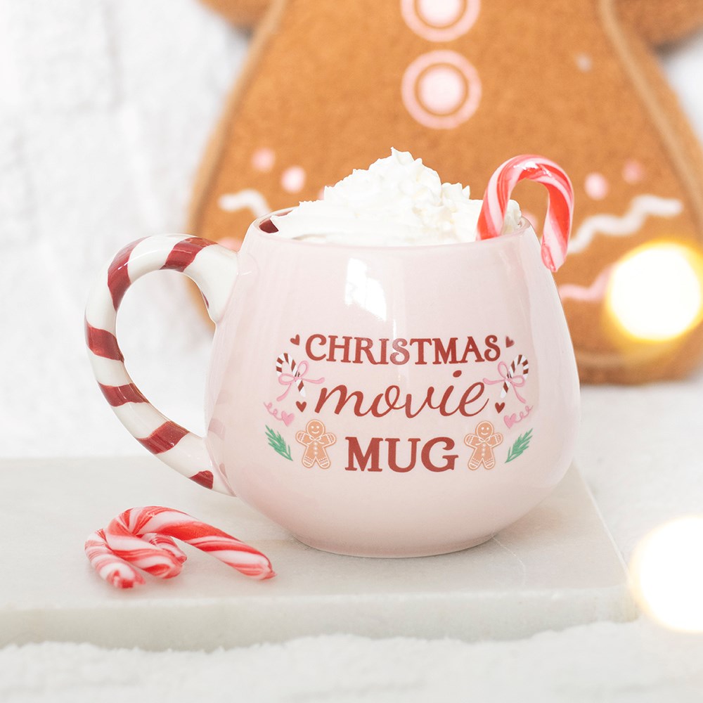 Pink Christmas Movie Mug with candy cane handle, whipped cream and festive gingerbread background