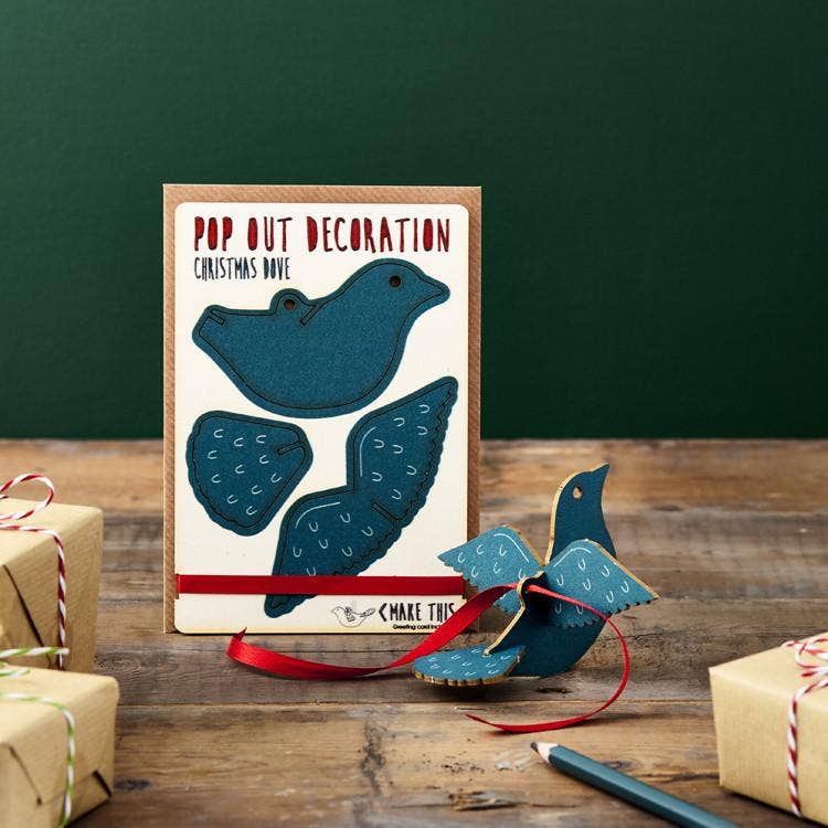 Pop Out Dove Christmas Card with assembled teal blue wooden dove decoration and red hanging ribbon in a festive setting