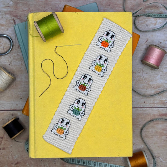 Pumpkin Ghosts Cross Stitch Bookmark Kit finished ghost bookmark styled on a yellow book with colourful sewing threads