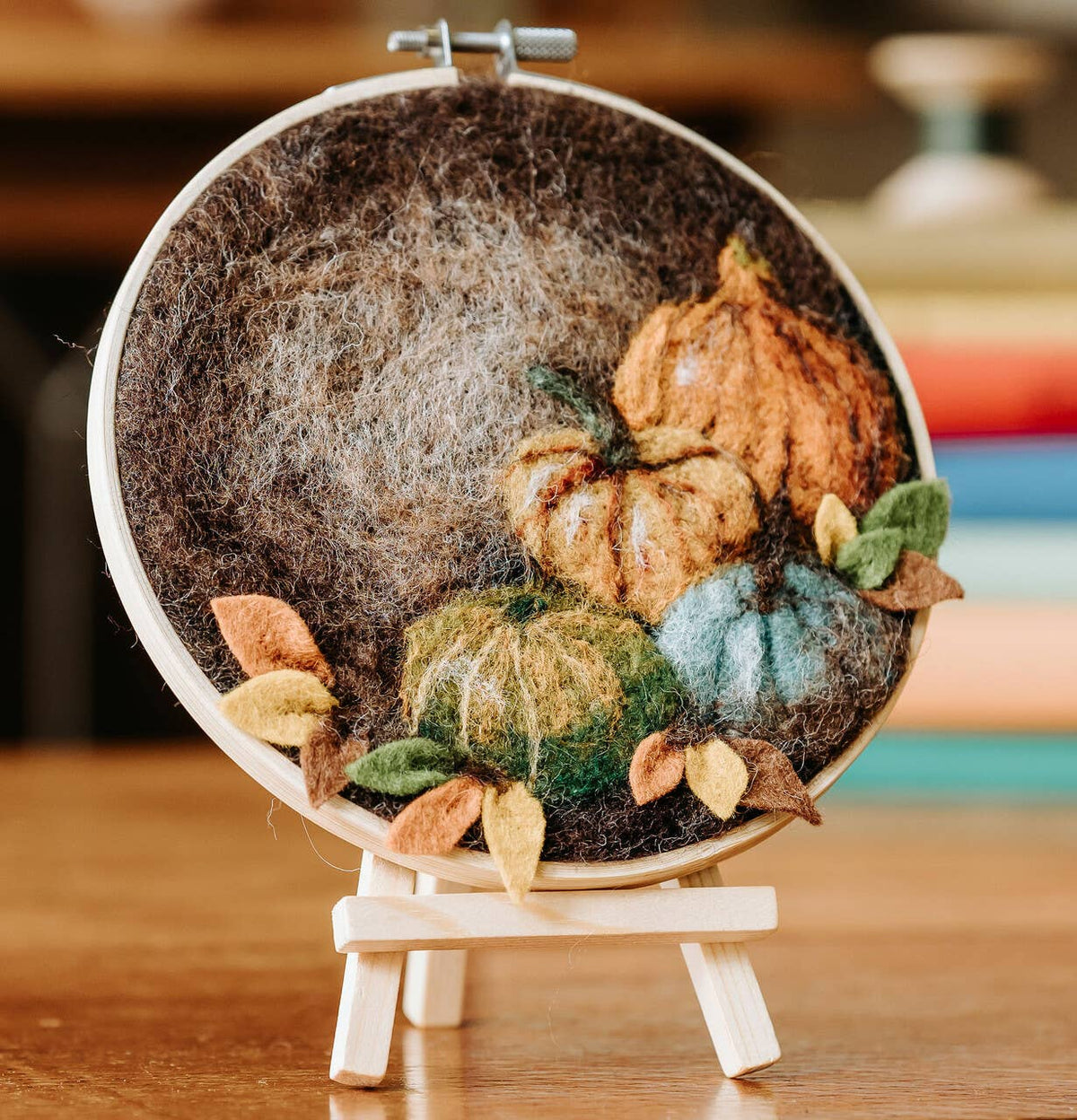 Paint with Wool Pumpkin Needle Felting Kit finished autumn pumpkin artwork displayed on a small wooden easel