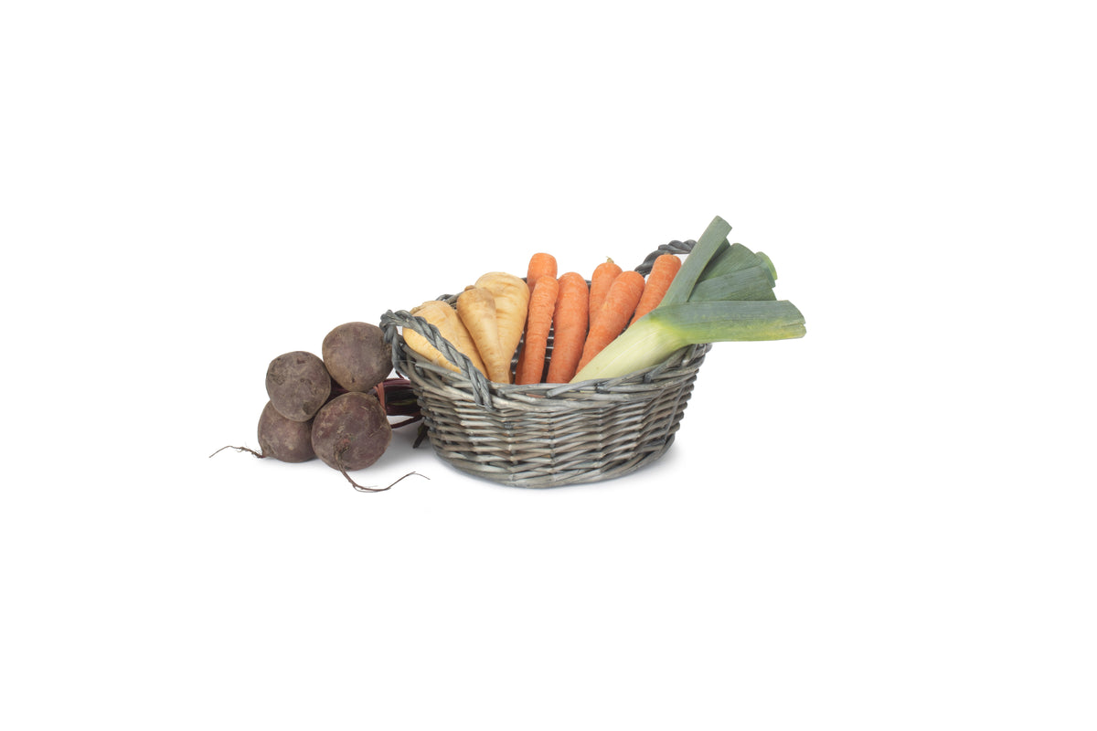 Small round antique wash willow display basket filled with carrots, parsnips and leeks, with woven handles