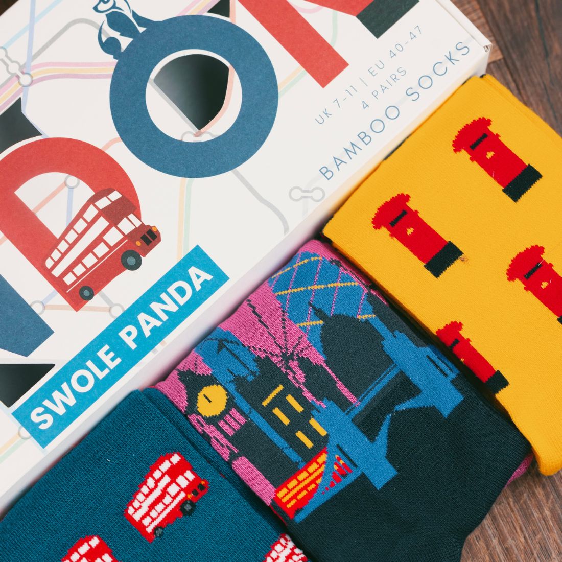 Colourful London-inspired Swole Panda bamboo socks displayed beside the gift box