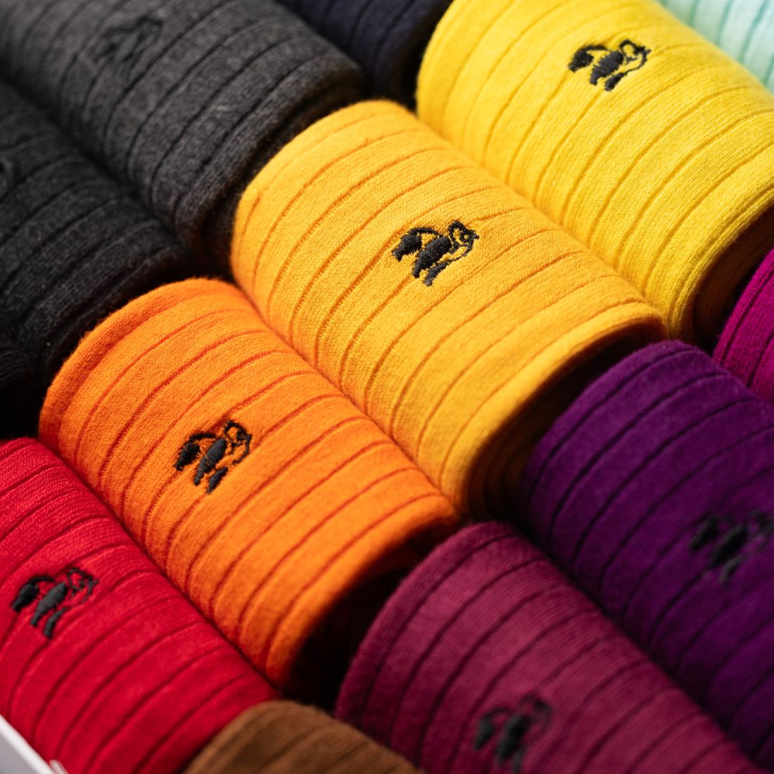 Orange, yellow and purple Swole Panda bamboo socks arranged inside the gift box