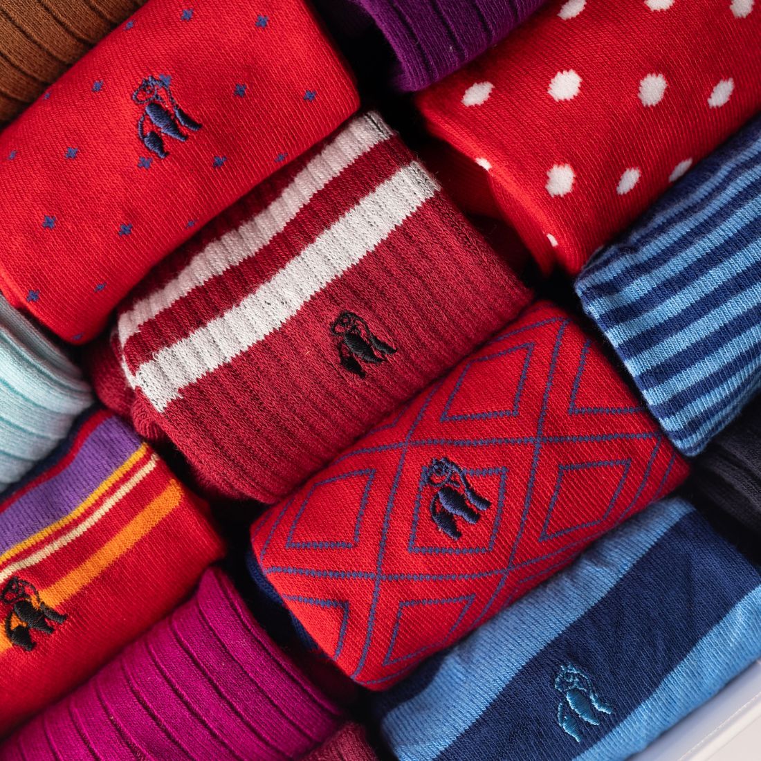 Close-up of red Swole Panda bamboo socks featuring assorted colourful patterns