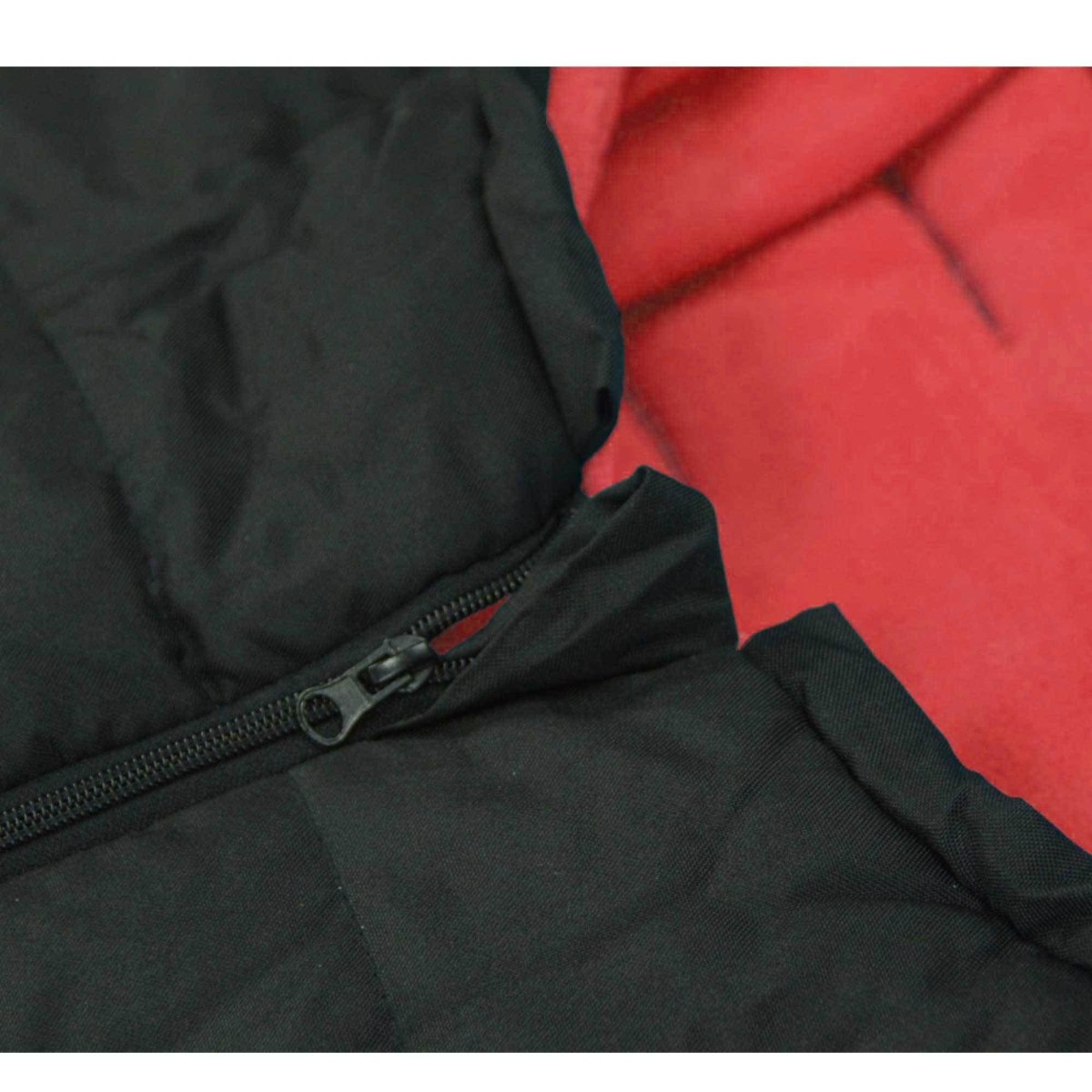 Close-up of a black footmuff with a zipper on a red background