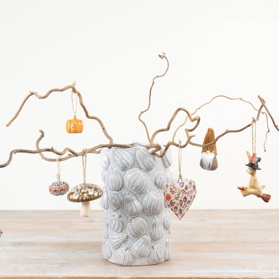 White pumpkin ceramic vase displayed with autumn branches in a seasonal interior