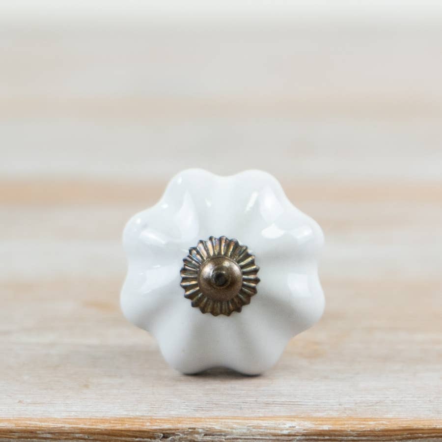 Front view of white scalloped ceramic door knob with decorative metal centre