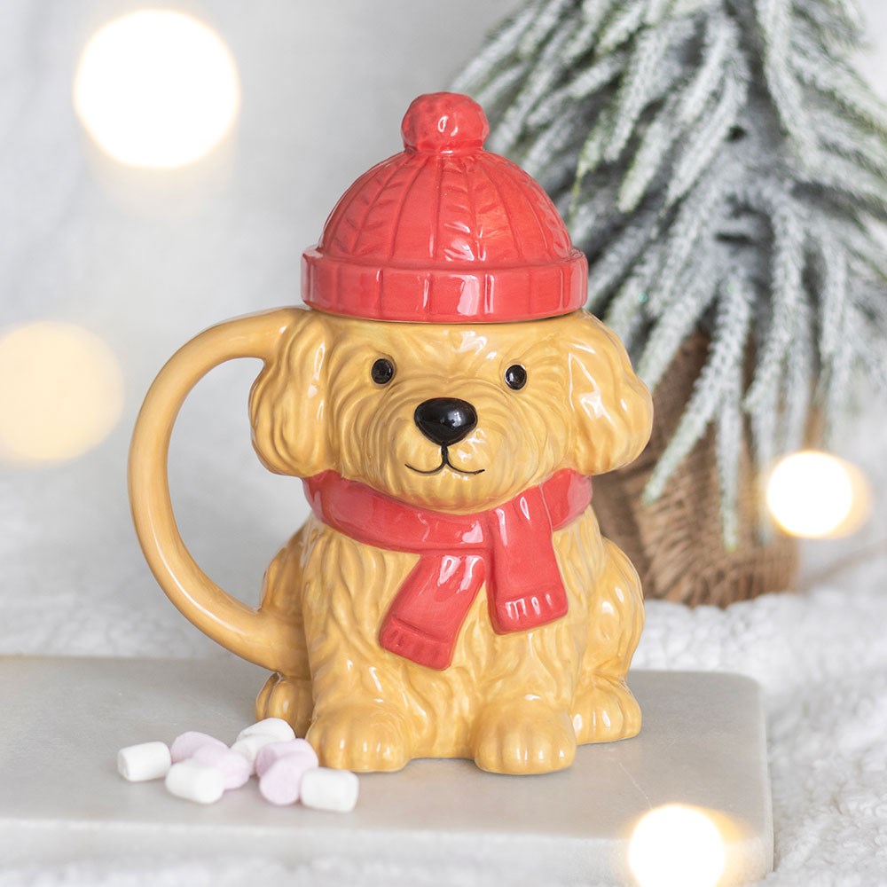 Winter Puppy Ceramic Mug with red bobble hat lid and matching scarf, displayed in a cosy winter setting with marshmallows