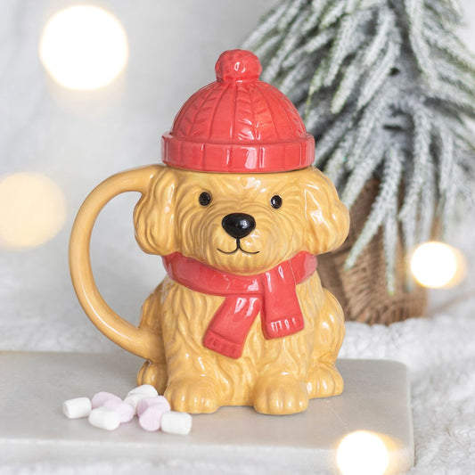 Winter Puppy Ceramic Mug with red bobble hat lid and matching scarf, displayed in a cosy winter setting with marshmallows