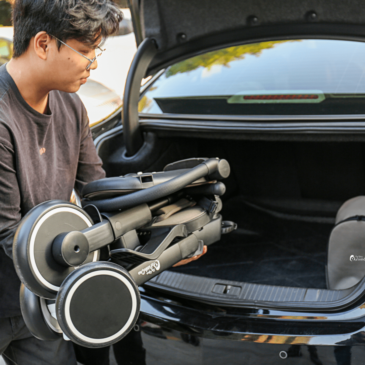 Xplor Ultimate 6 in 1 Foldable Trike in Jet Black being placed into a car boot after folding for transport